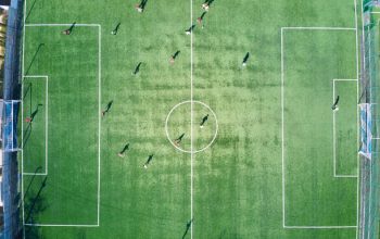 Aerial vieAw of soccer players playing football on green sports stadium. Aerial vieAw of soccer players playing football on green sports stadium.