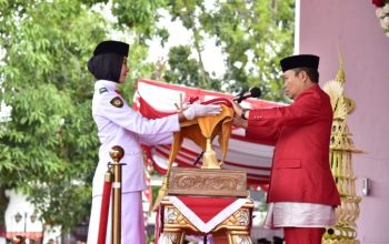 Penjagub Gorontalo Ismail Pakaya saat menerima bendera merah putih dari petugas pembawa baki, pada pelaksanaan Hari Ulang Tahun (HUT) ke-78 Republik Indonesia tingkat Provinsi Gorontalo, yang berlangsung di halaman rumah jabatan Gubernur Gorontalo, Kamis (17/8/2023). (Foto – Fikri)